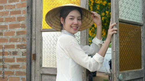 Smiling portrait Vietnamese woman wearing white national costume and hat poses and looks at the camera, video 4K
