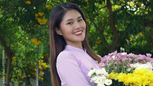 Beautiful Asian woman with long hair in pink Vietnamese dress smiling and looking at the camera, 4K video.