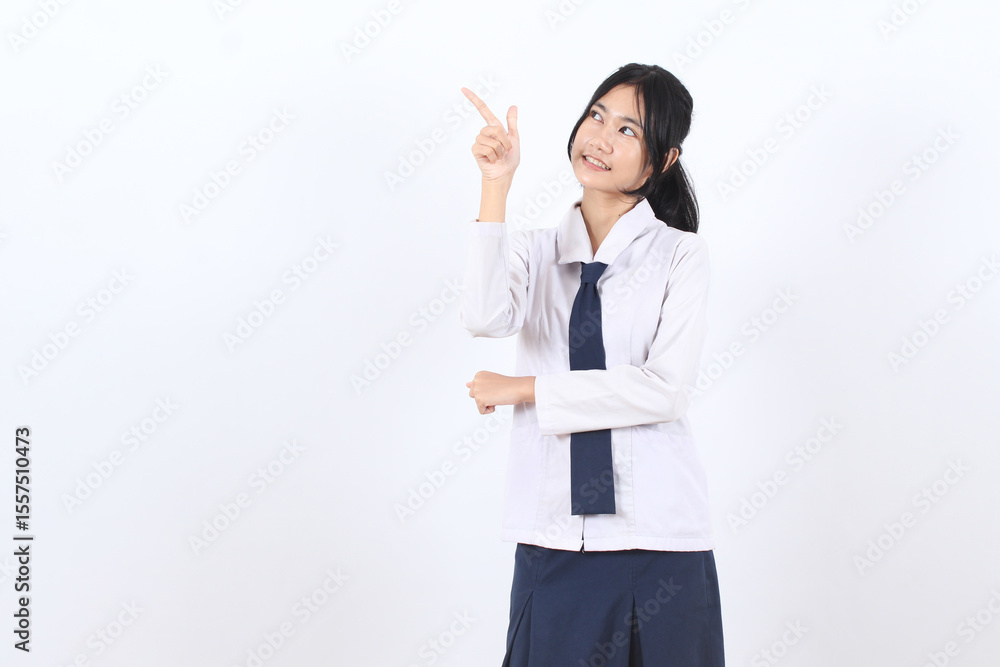 Asian teenage girl with long hair wearing school uniform pointing finger to empty space Asian teenage girl with long hair wearing school uniform pointing finger to empty space