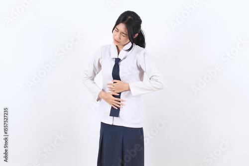 Asian student girl in school uniform suffering from stomach pain, touching belly with pained expression