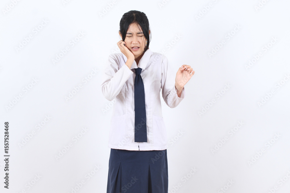 Asian student girl suffering from toothache, holding cheek with painful expression in school uniform Asian student girl suffering from toothache, holding cheek with painful expression in school uniform