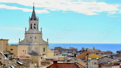 Wallpaper Mural Mediterranean-style coastal city with classic church tower and tiled rooftops under bright sunny sky, overlooking blue sea. Warm atmosphere of summer vacation Torontodigital.ca