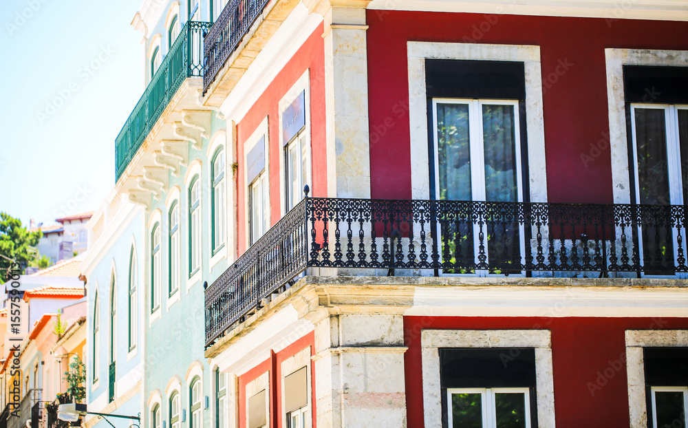 Naklejka premium Colorful traditional European buildings with wrought iron balconies in bright sunlight. A vibrant urban scene showcasing architectural details, pastel facades, and historic charm