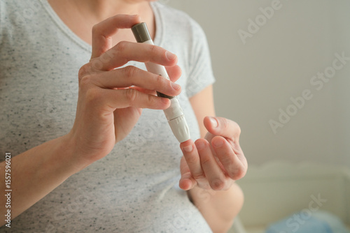 Canvas Print Close-up shot of pregnant woman testing her blood sugar with electronic device
