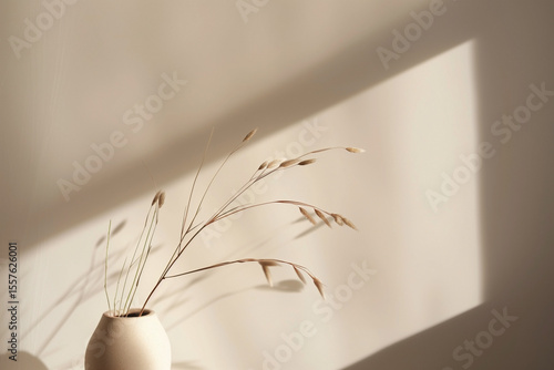 Minimalist vase with dried grasses, casting a soft shadow on a muted wall. Simple, elegant, and evocative of natural beauty.