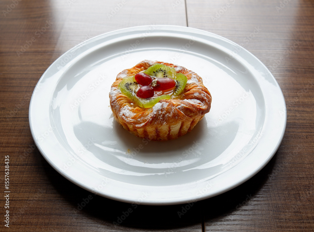 A Danish pastry topped with sliced kiwi and grapes from the Sunday market. A Danish pastry topped with sliced kiwi and grapes from the Sunday market.