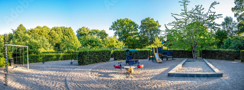 Sunny Children Playground With Swings, Slides, Sandbox, and Green Trees in a Peaceful Kildeparken Park, Aalborg, Denmark, 16 July 2018