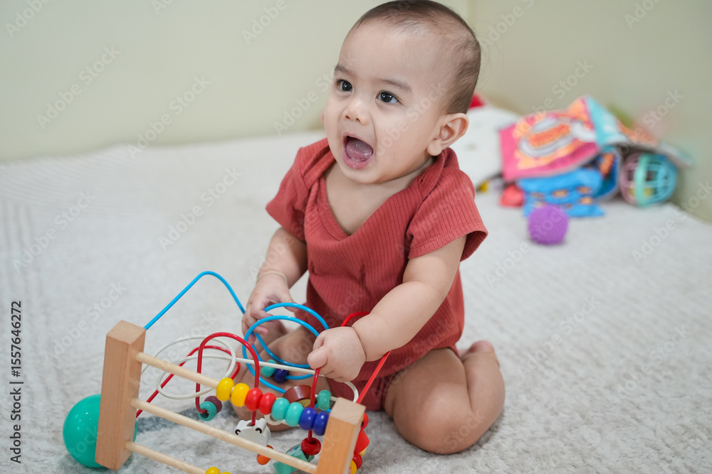Naklejka premium Happy baby with a colorful wooden toy maze, highlighting early childhood development and sensory learning.
