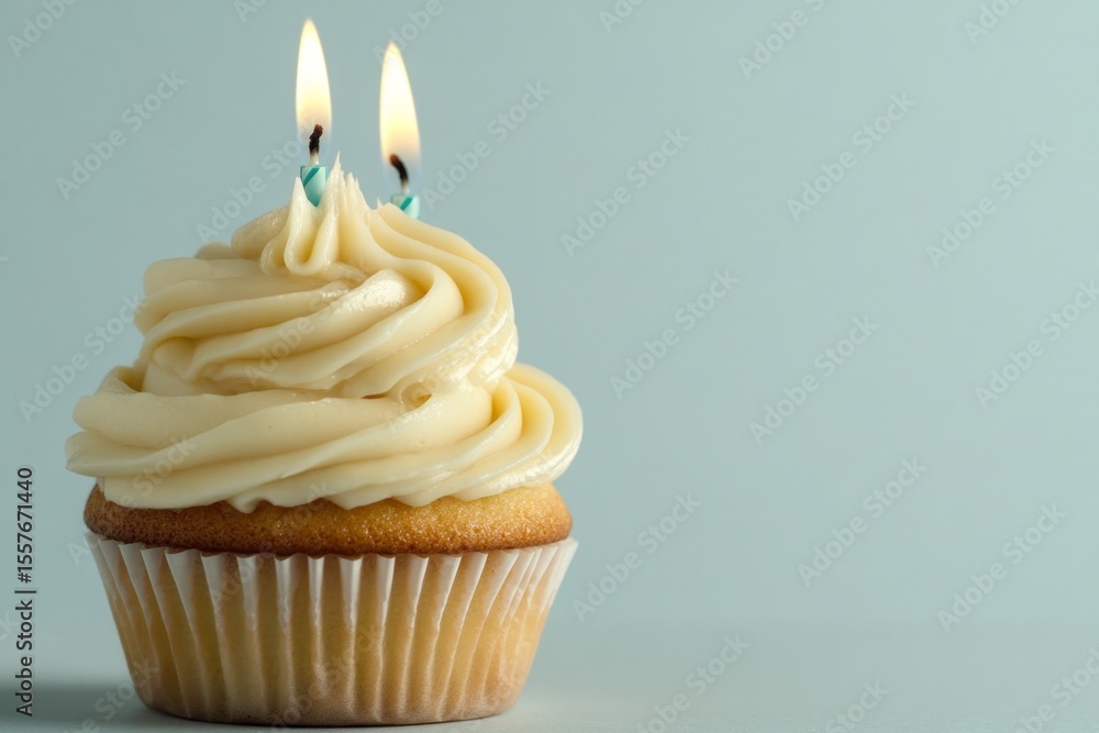 Vanilla Cupcake with Two Lit Candles on Light Blue Background Vanilla Cupcake with Two Lit Candles on Light Blue Background