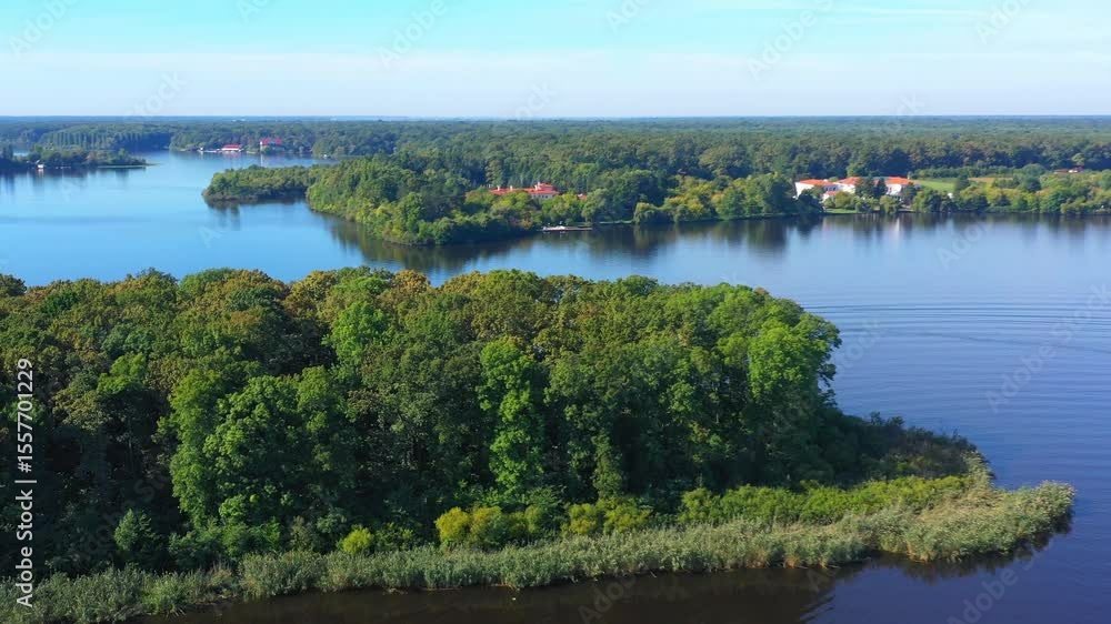A boat cruises on a tranquil lake, surrounded by forest. Sailing boat on the forest lake at sunset. Speedboat filmed from drone on Snagov lake at sunset.Lens flare, Aerial drone shot. A boat cruises on a tranquil lake, surrounded by forest. Sailing boat on the forest lake at sunset. Speedboat filmed from drone on Snagov lake at sunset.Lens flare, Aerial drone shot.