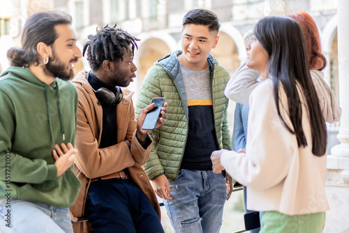 фотографія Multicultural group of young adults chatting and laughing together outdoors with