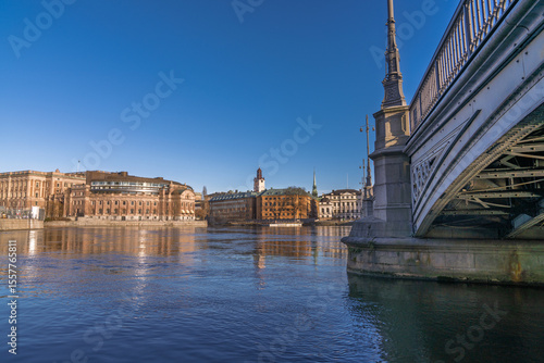 Swedish Parliament building reflected in water with bridge and skyline