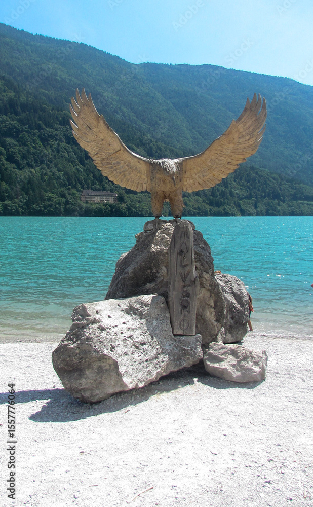 Fototapeta premium Wooden sculpture in the shape of an eagle on the shore of Lake Molveno in Trentino, Northern Italy. The eagle is the animal symbol of the city