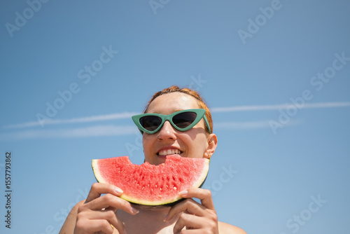 Tourist enjoying watermelon slice on sunny beach