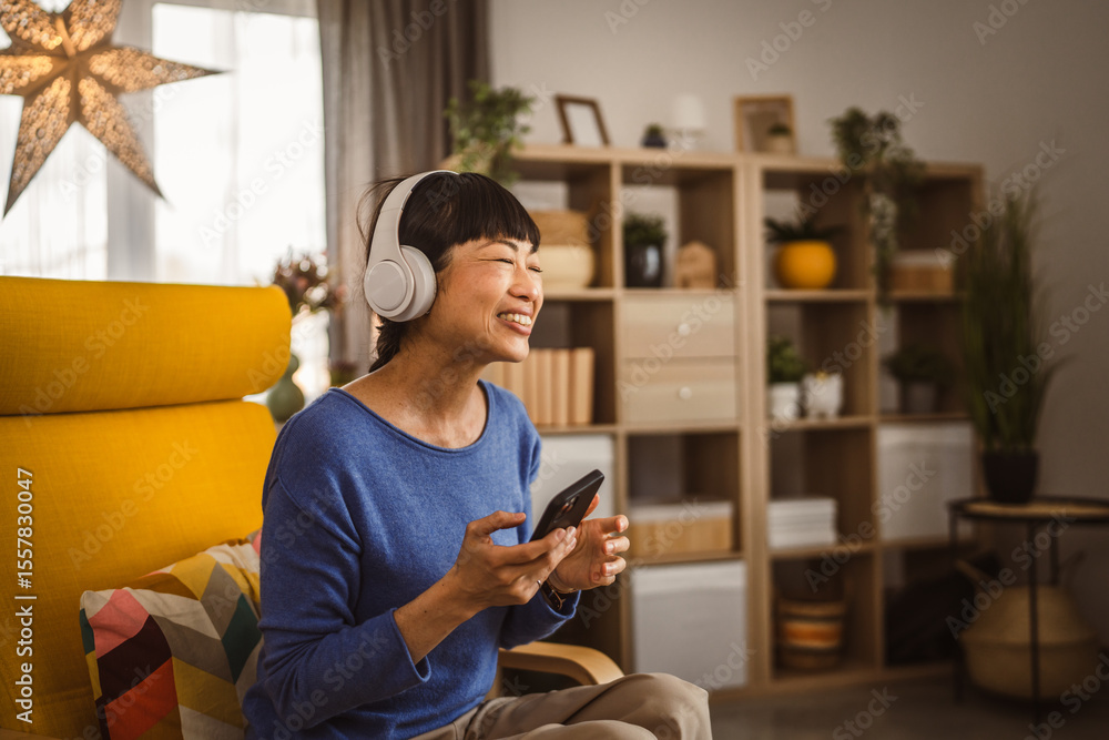 Obraz premium Mature japanese woman with headphones listen music on mobile phone