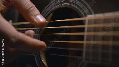 The guitarist’s fingers play on the guitar strings