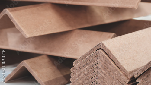 Fotografía Stack of cardboard corner protectors for packaging, corners are brown and arranged in a row as background templates of pages and banners of delivery logistics concept