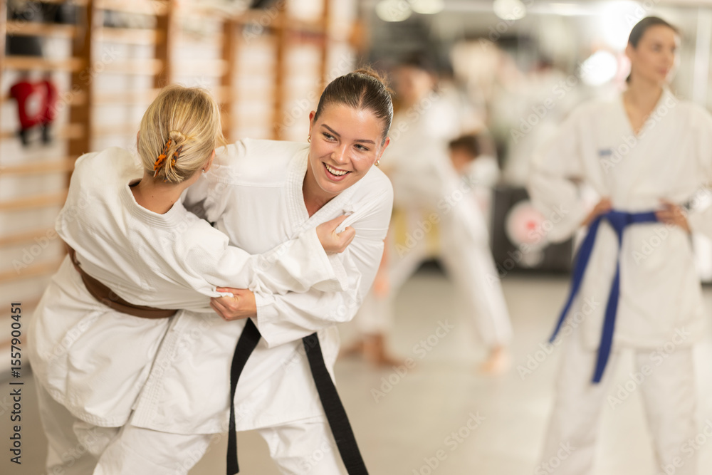 Fototapeta premium Young women in kimonos practice judo. Women practice wrestling. Group Judo Training