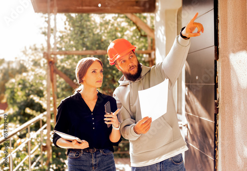 construction worker and client architect at a construction site inspect plan use tablet.architect and builder in a house under construction check the quality of work plan inspect