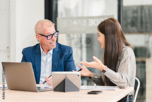 Wallpaper Mural Two businesspeople having lively discussion in modern office with laptop and tablet on table, showing positive and engaged communication Torontodigital.ca