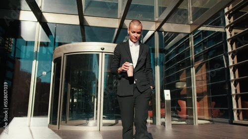 Wallpaper Mural A businesswoman exits a revolving door of a modern office building while holding a coffee. She walks forward with confidence, ready to start her workday. Torontodigital.ca