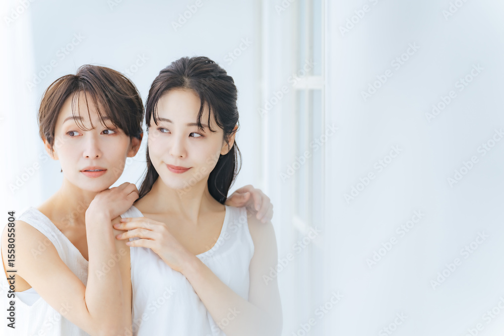 明るい部屋で寄り添う白いワンピースを着た二人の女性 明るい部屋で寄り添う白いワンピースを着た二人の女性
