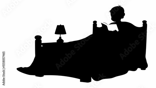 Silhouette of a child reading a book in bed next to a lamp on a nightstand in a dark room at night