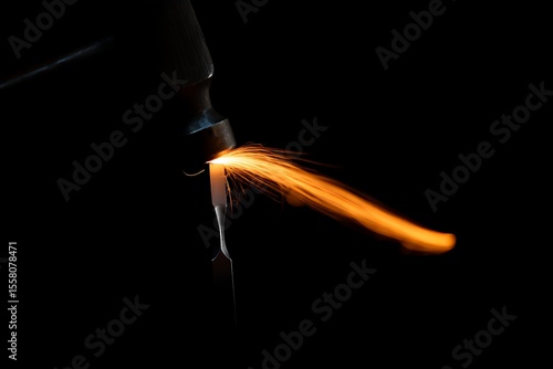 Welding sparks flying from metal tool on black background