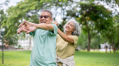 Fotografie Old woman massaging glasses man shoulders while he standing and stretching on gr