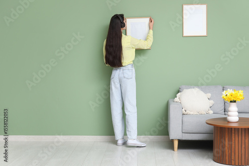 Young woman hanging picture...