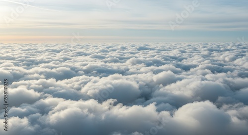 View from above the clouds during sunset, a serene and ethereal landscape filled with soft, fluffy white clouds stretching to the horizon under a warm sky.