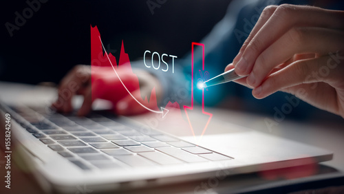 Close-up of a person using a pen on a laptop with a cost reduction graph overlay. Concept of lowering expenses, saving money, and efficient financial planning in business.
