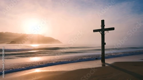 Serene sunset at a beach with a wooden cross, gentle waves, and misty hills in the background