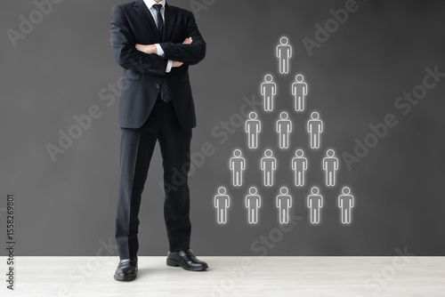 腕組みをするビジネスマンとピラミッド型の組織図―人事に関して考えるイメージ