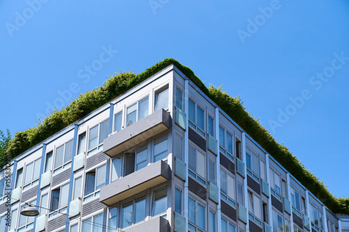 Urban building features a lush green roof against a bright blue sky, highlighting eco-friendly design principles.
