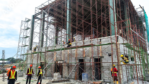 The construction workers working at height at the construction site. Using scaffolding as temporary platform to work. Selective focus. 
