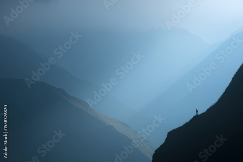 solitary figure standing on edge of cliff gazing at mountain ridge in peru