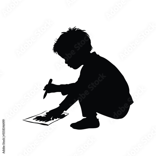 Silhouette of a young boy drawing on paper with a pencil