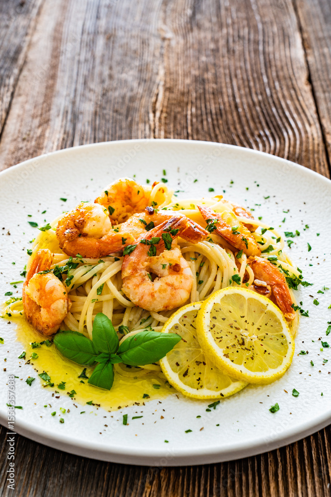 Spaghetti with fried shrimps, olive oil and parsley on wooden table Spaghetti with fried shrimps, olive oil and parsley on wooden table