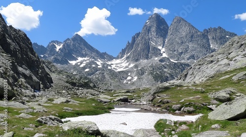 Wallpaper Mural Majestic mountain range with snow-capped peaks, a valley with a small stream, and green meadows under a bright blue sky Torontodigital.ca