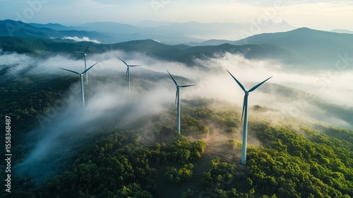 Majestic wind turbines stand tall amidst a misty mountain landscape, showcasing clean energy amidst nature's beauty
