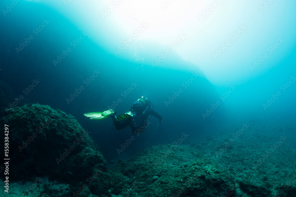 diver diving over near the seabed rocks, concept of scuba diving and underwater adventure, copy space for text diver diving over near the seabed rocks, concept of scuba diving and underwater adventure, copy space for text