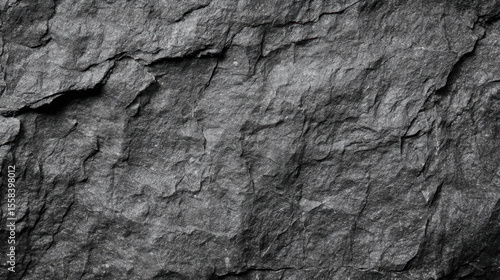 Dark gray granite rock texture showcasing cracked and rough mountain surface patterns