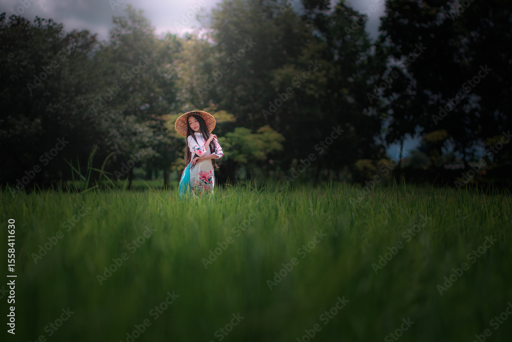 Obraz premium Vietnamese Girl in Traditional Attire Standing in a Rice Field