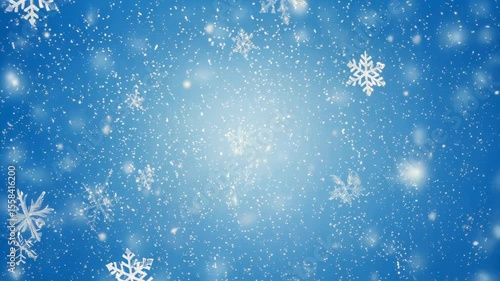 Delicate snowflakes gently falling against a soft blue background create a magical winter atmosphere.
