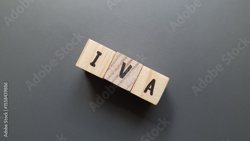 IVA acronym made of wooden letter cubes on dark background. Impuesto sobre el Valor Añadido (Value Added Tax, VAT)