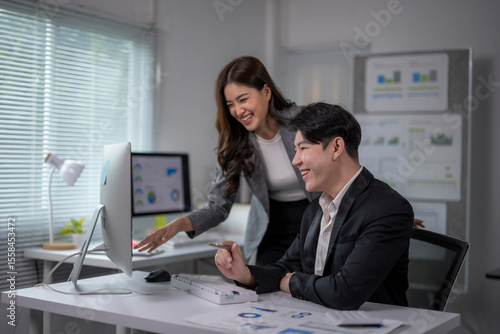 Fotografía woman and a man are sitting at a desk with a computer monitor in front of them