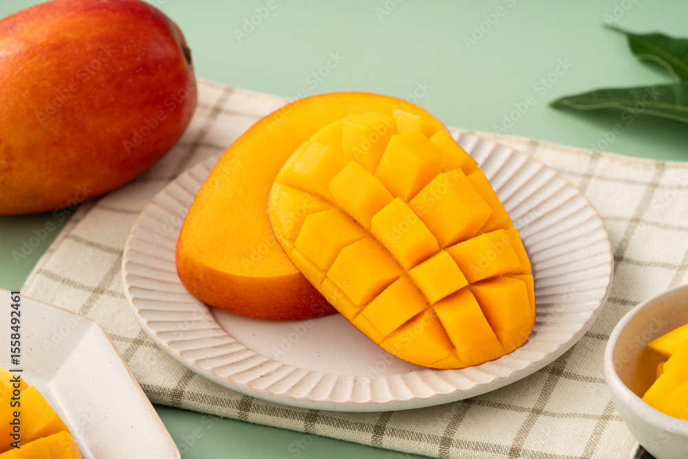 Fototapeta premium Fresh ripe mango with cubes on green table background.