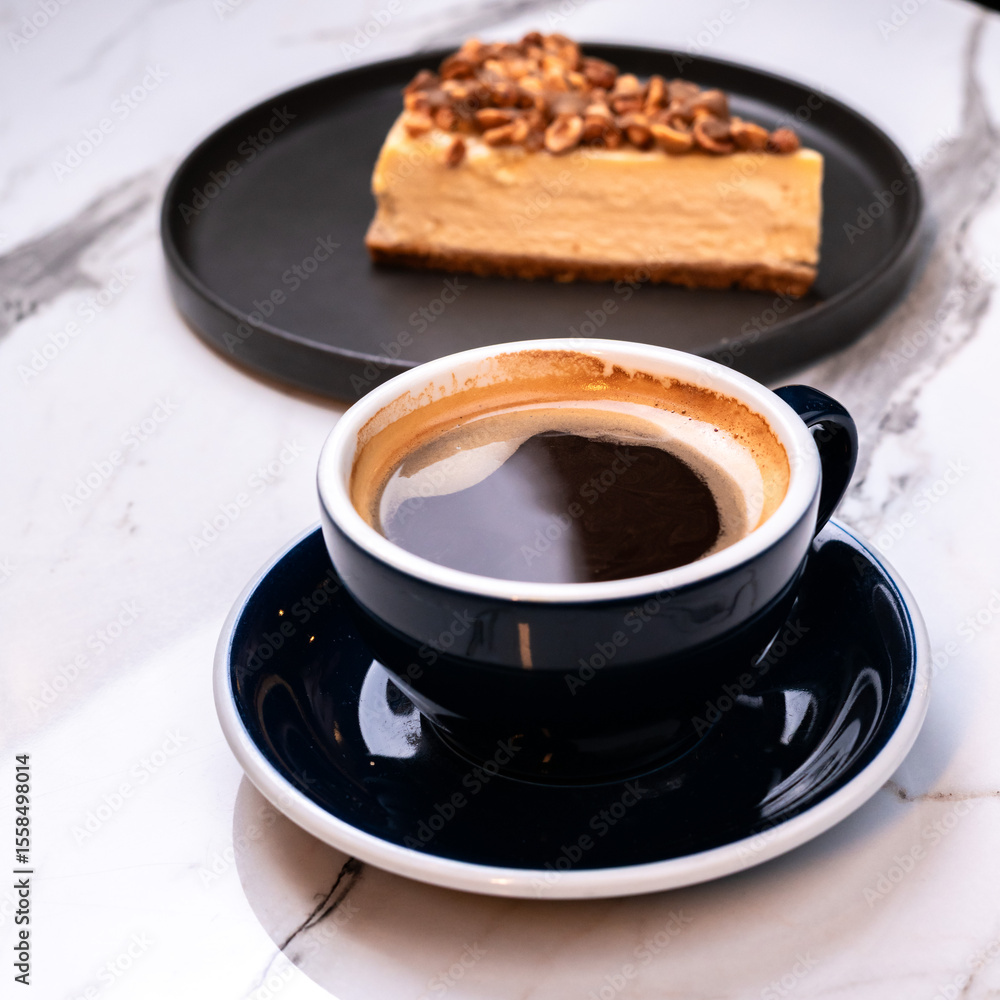 Fototapeta premium Mocha black coffee with hazelnut cheesecake slice on marble table