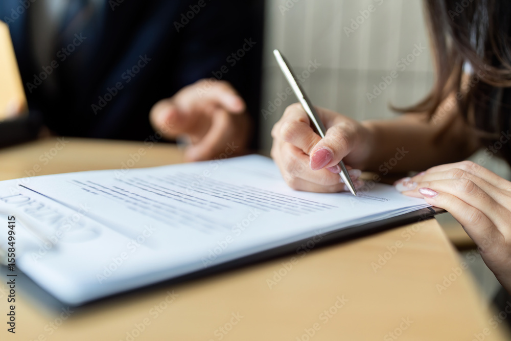 Document Signing. Close-up of a woman signing a contract in a professional setting. Document Signing. Close-up of a woman signing a contract in a professional setting.